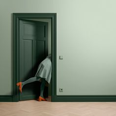 a woman is hiding behind an open door with her legs in the floor and feet on the wall