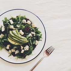 a salad with avocado, feta cheese and cranberries on it