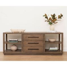 an entertainment center with drawers and shelves on the bottom, in front of a white wall