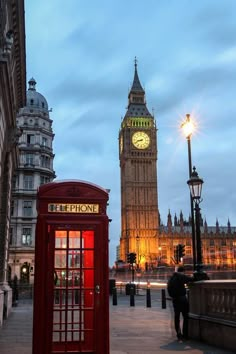 the big ben clock tower towering over the city of london, england at dusk with a red phone booth