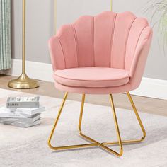 a pink chair sitting on top of a white rug next to a gold metal frame