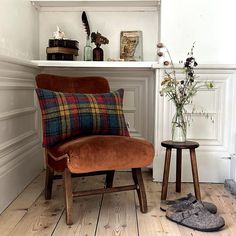 a brown chair sitting next to a wooden table with flowers on top of it and a pair of slippers