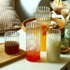 four glasses filled with liquid sitting on top of a table