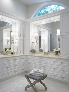 a large bathroom with white cabinets and marble counter tops, along with an ottoman in the middle