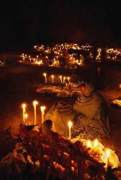 people are sitting in the dark with candles lit up around them and one person is laying on the ground