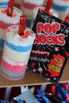 red, white and blue cupcakes in plastic cups with candy sticks sticking out of them