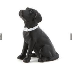 a black dog figurine sitting on the ground with its head turned to the side