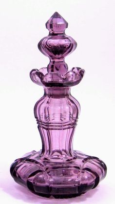 a purple glass vase sitting on top of a white table