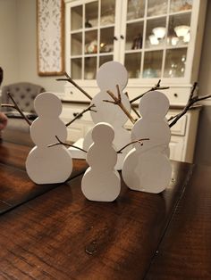 snowmen made out of paper sitting on top of a wooden table