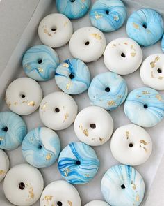 a box filled with white and blue donuts covered in gold sprinkles