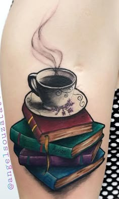 a cup of coffee and books tattoo on the right side of the thigh, which is covered in black ink