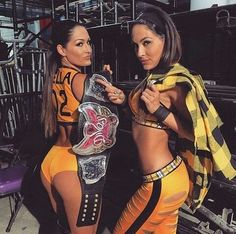 two beautiful women standing next to each other holding a wrestling ring and looking at the camera