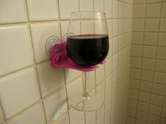 a glass of wine sitting on the side of a wall next to a bathtub