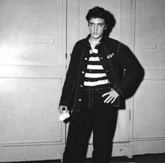 black and white photograph of a young man standing in front of lockers with his hands on his hips