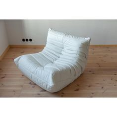 a white couch sitting on top of a hard wood floor next to a wall with two black knobs