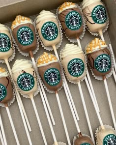 starbucks cupcakes and marshmallow pops are arranged on sticks in a box