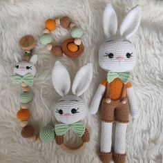 two crocheted stuffed animals sitting next to each other on a white rug with wooden beads