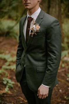 a man wearing a suit and tie standing in the woods