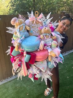 a woman standing in the grass holding a large bouquet of teddy bears and other items