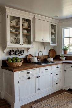 a kitchen with white cabinets and wooden counter tops, an area rug on the floor