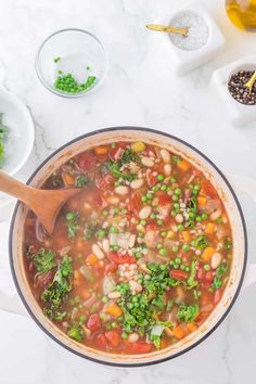 a pot filled with beans, broccoli and other vegetables on top of a white counter