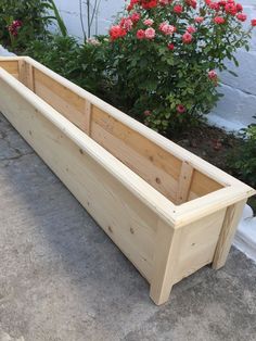 a wooden planter sitting on the ground next to flowers