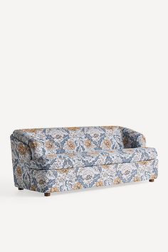 an upholstered couch with blue and orange floral print on the back, against a white background