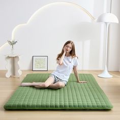 a woman sitting on the floor in front of a green mat