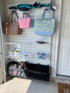 several bags hanging on the wall in front of a door with shoes and handbags