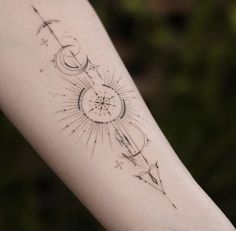 a woman's arm with an arrow and compass tattoo on the left side of her arm