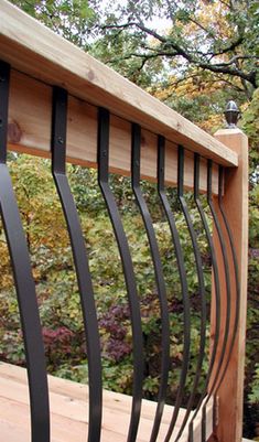 a wooden fence with black iron bars on it and trees in the backround