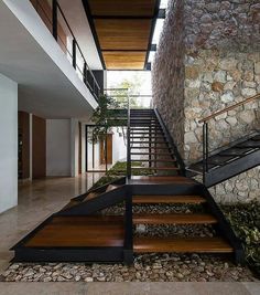 there is a stair case in the house with rocks on the floor and wood steps leading up to it