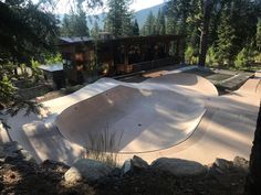 an empty skateboard park in the woods with trees and rocks around it's edge