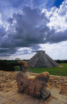 an ancient statue sitting on top of a stone floor in front of a large pyramid