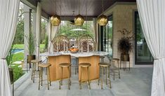 an outdoor dining area with marble top table surrounded by gold stools and hanging lights