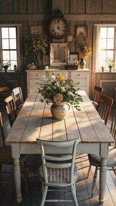 a wooden table with chairs around it and a vase filled with flowers sitting on top of it