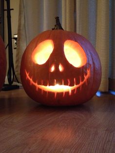 two carved pumpkins sitting on top of a wooden table with their faces glowing in the dark