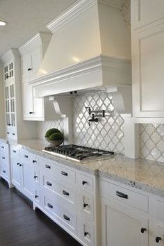 a kitchen with white cabinets and marble counter tops