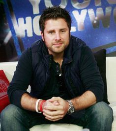 a man sitting on top of a white couch in front of a blue and red sign