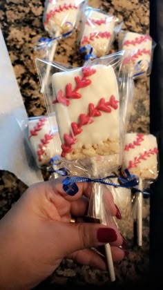 a person is holding up some baseball themed cookies and marshmallows in plastic wrappers