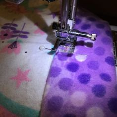 the sewing machine is on top of the purple and white fabric with polka dot designs