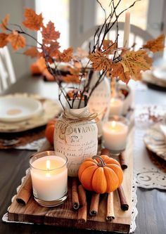 a wooden tray topped with candles and pumpkins