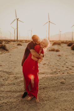 a man and woman hugging in front of windmills