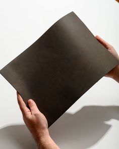 a person holding a piece of brown paper in their left hand, on a white background