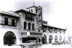 an old movie theater with cars parked in front