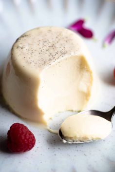 a piece of cheese and some raspberries on a white plate with spoons