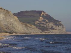 there is a large rock outcropping on the side of the beach near the ocean