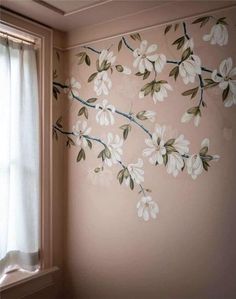 a wall with flowers painted on it next to a window