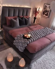 a large bed sitting in a bedroom next to two candles on top of each other