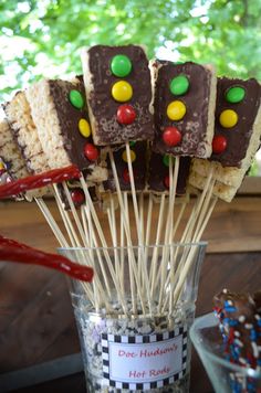 there are many pieces of cake on sticks in a glass cup with candy and marshmallows